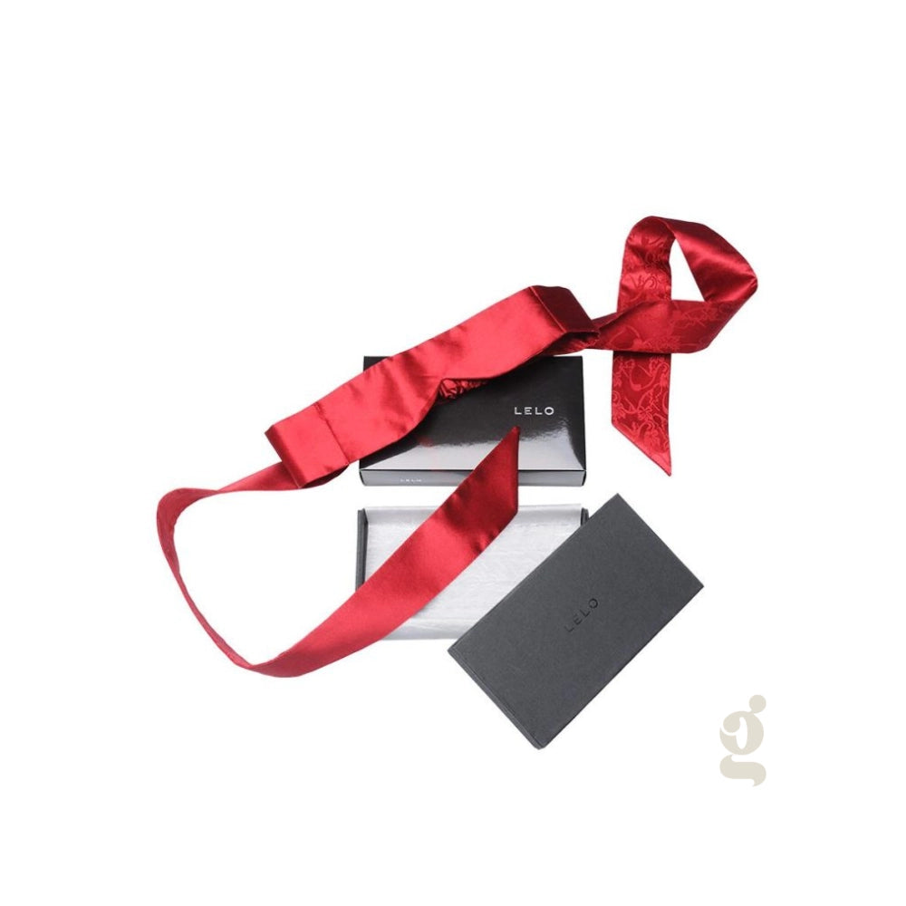 Antifaz de seda roja Intima Silk de LELO junto a su empaque de lujo negro para catálogo Gimo.